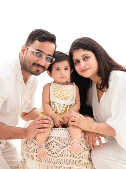 A classic family portrait in coordinated white outfits. The clean, minimalist setup allows the family's connection and happiness to be the main focus.