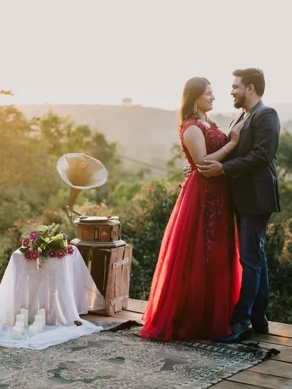 A classic romantic pose against a stunning natural landscape, showcasing the elegant red gown and the beautiful styling of the shoot.