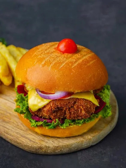 A different angle of a veggie burger and fries, focusing on the layers within the burger. The dark styling is consistent and effective for creating a cohesive brand look.