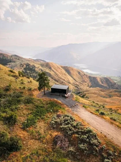 An aerial shot capturing the solitude and beauty of a single modular home placed in a vast, hilly terrain. This is off-grid living without sacrificing modern comforts.