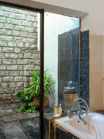 Another view of an open-air bathroom, showing the blend of stone, plants, and modern fixtures.