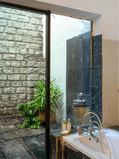 A look into the open-air shower space, with its stone walls and greenery, offering a unique and refreshing experience.