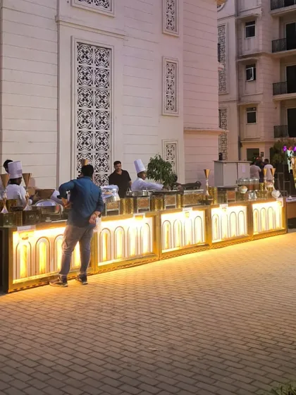 Guests enjoying the food from our stylish, lit-up buffet counters. This setup is perfect for modern weddings, corporate parties, and receptions, adding a sophisticated ambiance to the dining area.