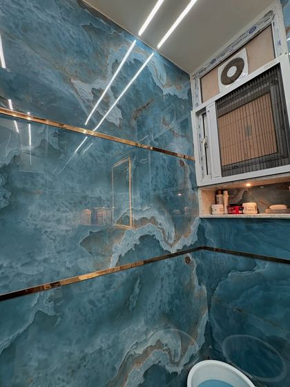 A detailed shot of the blue marble-look tiles with gold inlay, creating a dramatic and high-end finish in the shower area.