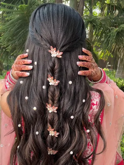 A beautiful half-up, half-down hairstyle for an engagement. The delicate braid is adorned with pearls and floral clips for a romantic touch.