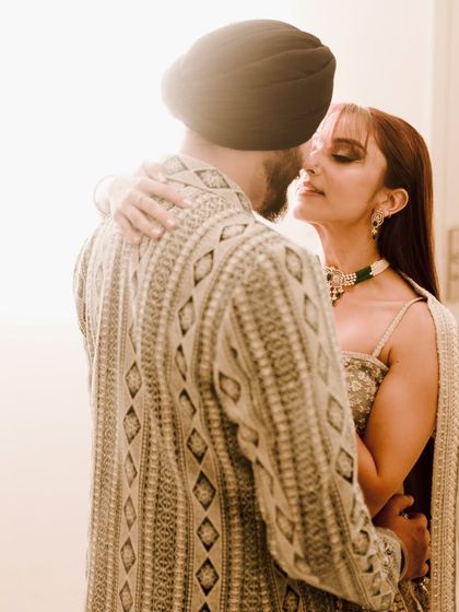 An intimate and beautifully backlit portrait. The soft flare of light envelops the couple, creating a dreamy and romantic atmosphere that highlights their close embrace.