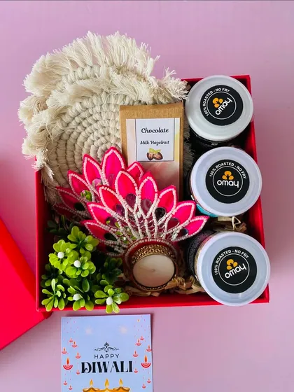 This red box hamper is packed with three jars of Omay snacks, a chocolate bar, macrame coasters, and a beautiful peacock-themed T-light holder.