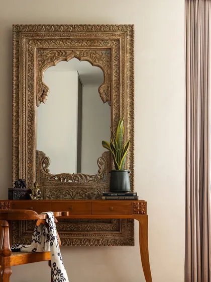 A full view of the statement carved mirror, which acts as a piece of art and brings a sense of history and grandeur to the space.