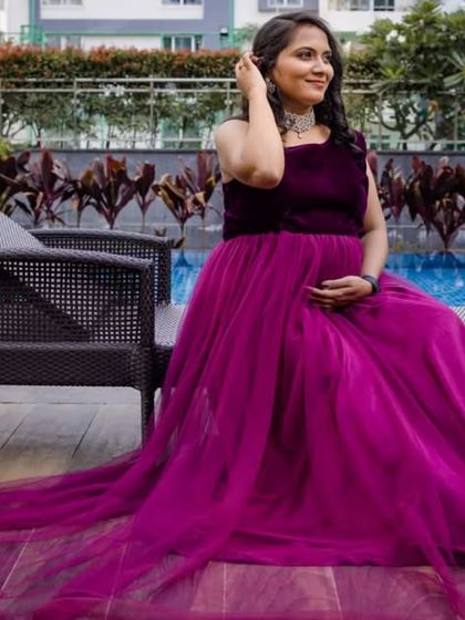 A relaxed poolside maternity photo. The client looks elegant in this deep magenta velvet and tulle gown, perfect for a sophisticated pregnancy shoot.