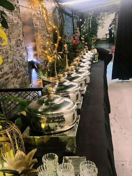 A long-shot of an elegant black and gold themed buffet for 70 guests in Maharani Bagh. The setup is designed to look grand and inviting, stretching across the venue space.