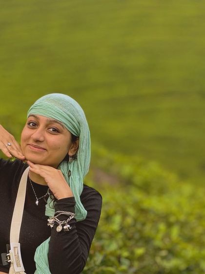 A traveler posing against the backdrop of a lush tea plantation in Munnar.