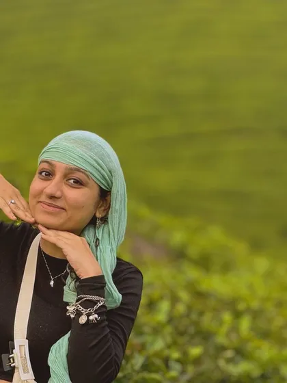 A traveler posing against the backdrop of a lush tea plantation in Munnar.