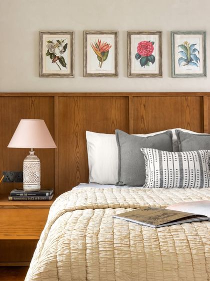 In one of the guest bedrooms, a series of botanical prints is mounted above a simple wood-paneled headboard, adding a touch of color and personality.