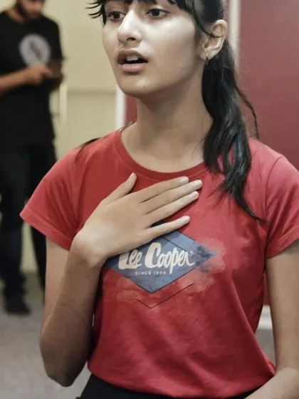 A candid shot of a student during a vocal warm up, focusing on her breath and posture. These are the foundational moments of learning to sing well.
