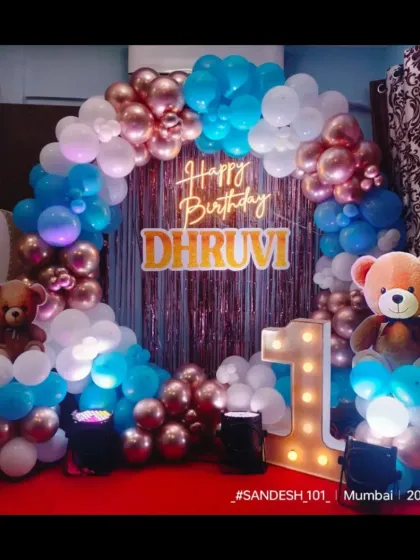 A sweet teddy bear themed first birthday party. A circular balloon arch in rose gold, blue, and white is decorated with cute teddy bears and a hot air balloon prop.