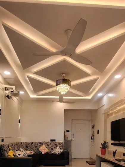 The finished look of a geometric false ceiling design in a Mysore home. The combination of recessed lights and a modern fan creates a bright and airy living space.