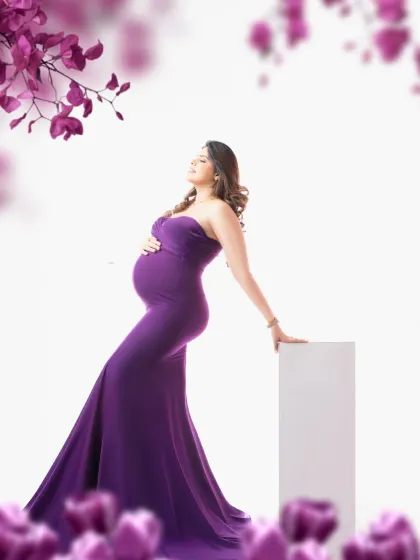 A regal portrait in a deep purple gown. The floral framing adds a soft, romantic touch to this elegant and colorful maternity photograph.