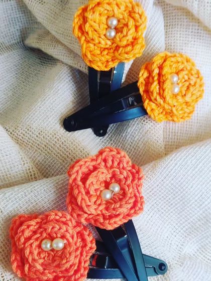 A pair of orange and coral floral hair clips, each adorned with tiny pearls. These make a lovely, handmade gift.