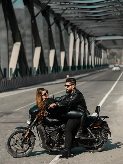 For the modern, adventurous couple, a pre-wedding shoot with an edge. This shot captures a cool, confident pose on a Harley Davidson against the industrial backdrop of a bridge, telling a story of love and shared passions.