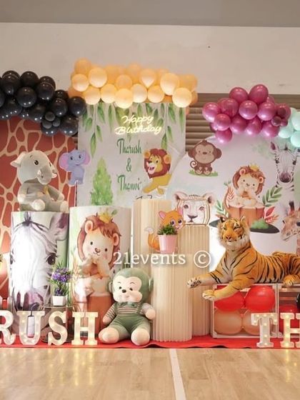 A softer, pastel take on the jungle theme for a joint birthday party. This setup uses plush animal toys, lighter-colored balloons, and a giraffe-print arch to create a sweet safari vibe.