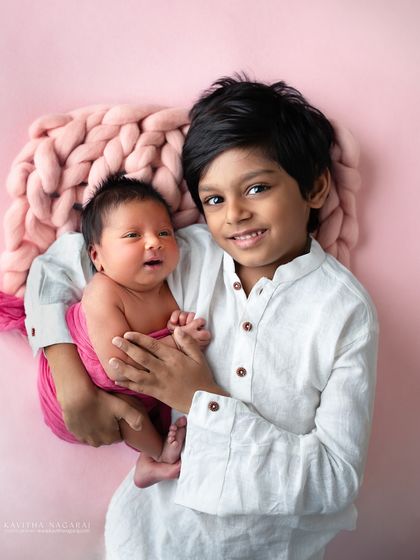 A proud big brother holds his three-week-new baby sister. The bond between siblings is so special, and capturing these early moments of love and protection is priceless.