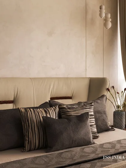 The art of styling throw pillows. This image showcases a beautifully layered bed with a mix of striped and textured grey cushions against a soft, upholstered headboard.