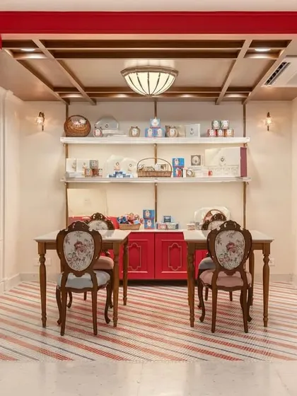 For the Parsi Dairy Farm renovation, I wanted to create a space that felt familiar yet fresh. This gifting zone, with its custom red cabinetry and floral upholstered chairs, is a cozy corner where customers can assemble hampers or enjoy a treat. It’s a perfect example of blending charming, old-world features with a clean, modern aesthetic.