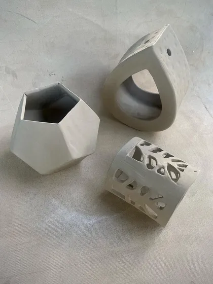 A collection of unfired, hand-built pieces from our Level 1 course. You can see a variety of forms, including a geometric planter and a carved luminary, showcasing different techniques.