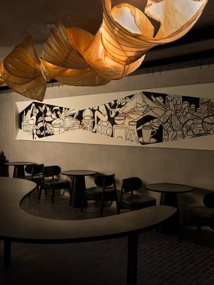 The full artwork in the context of the cafe's moody and modern interior, complemented by sculptural paper lanterns.