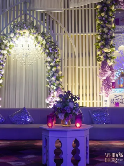 A cozy seating area from the lavender-themed engagement. The plush sofa is accented with sequined cushions, and the space is softly lit by purple-hued candles, creating an intimate and glamorous corner.