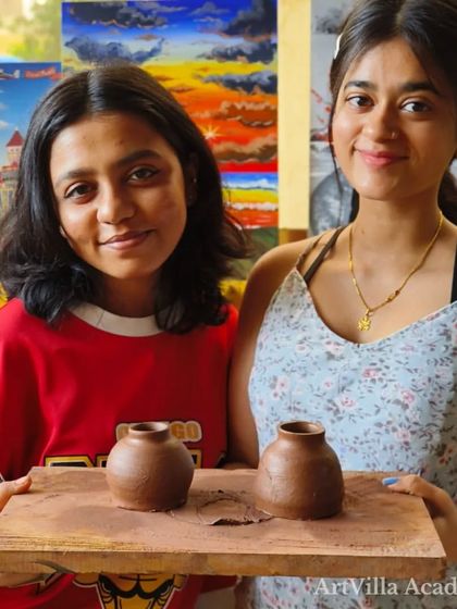 Two students hold up their matching handmade pots, created during a single session. Our workshops are a great way to spend quality time with friends or family.