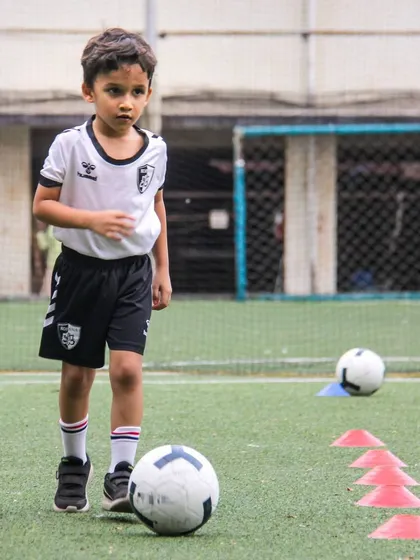A young player dribbles through a line of mini cones, a drill that enhances precision and quick footwork.