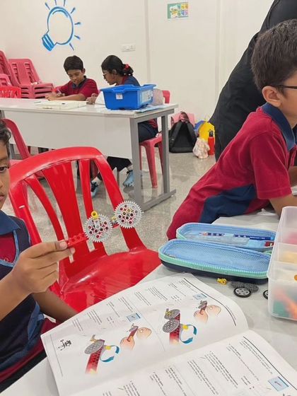 A student at Vidyashilp Academy proudly displays the gear mechanism he has just built, a key component in understanding how machines work.