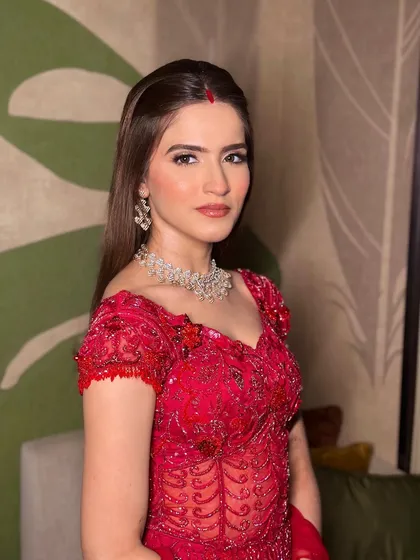A confident portrait of the bride in her red reception gown. The makeup is sharp and clean, with a focus on perfect skin and defined features.