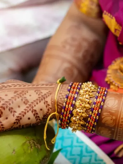 This image captures the beauty of a traditional South Indian ceremony. The mehendi features a classic jaali (net) pattern on the back of the hand, with solid-colored fingertips for a striking contrast.