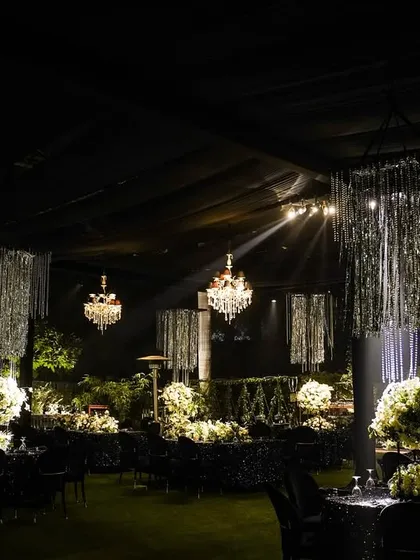 A wide shot of a cocktail party setup, where I used a combination of crystal chandeliers and silver tassel chandeliers over black sequined tables to create a sparkling, festive atmosphere.