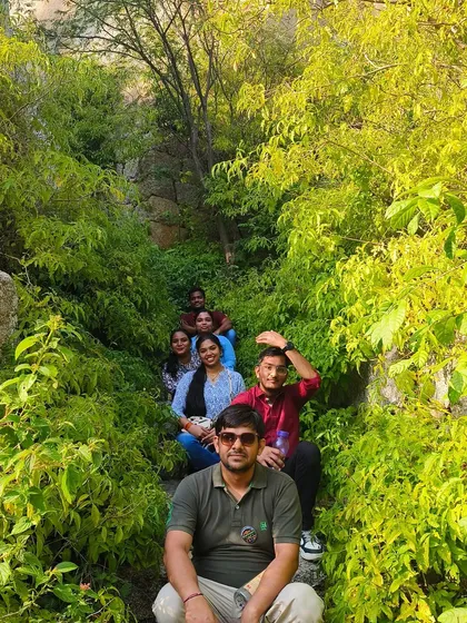 A group posing for a photo in a narrow, green passage on a hill trek.