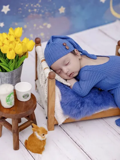 A duplicate of our starry night theme, this shot shows a slightly different angle of the newborn sleeping in a miniature bed. The setup includes tiny felt Starbucks cups for a playful touch.