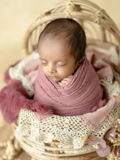 Pretty in pink. A beautifully swaddled newborn rests in a rustic basket, showcasing the delicate textures and soft colors I use in my sessions.