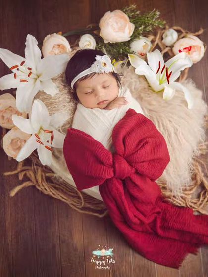 We love using flowers to frame these precious faces. This newborn is wrapped like a little gift with a big red bow, surrounded by beautiful white lilies.