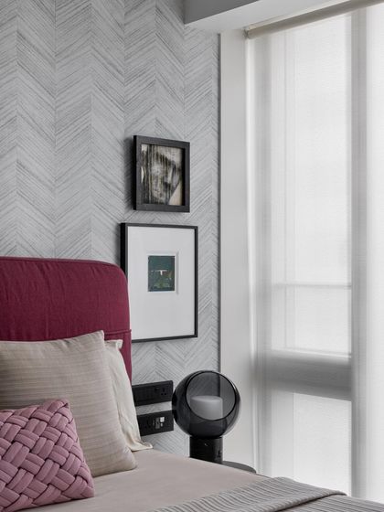 Good design is a language, not a style. This bedroom corner showcases that philosophy with its chevron-patterned wallpaper, magenta headboard, and carefully curated art, creating a space that is both chic and timeless.