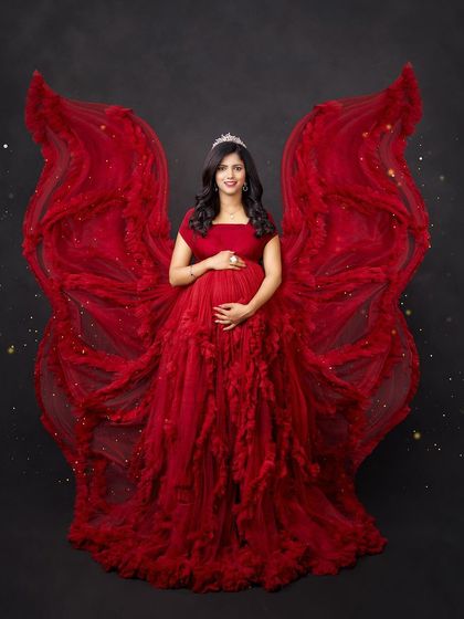 A powerful and angelic portrait. The dramatic red ruffled gown is styled to look like wings, creating a stunning and symbolic image of a mother's strength.