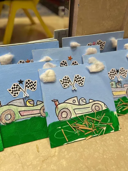 The finished race car canvases, decorated with cotton clouds and toothpick grass. I love seeing the creative details the kids add.
