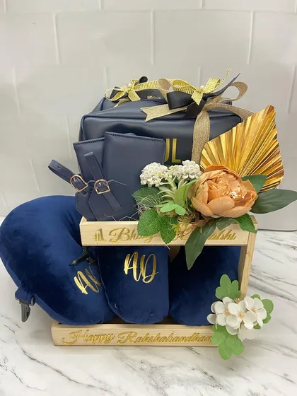 The complete travel-themed hamper for a couple, featuring personalized slippers, a travel pillow, and matching pouches, all beautifully arranged in a wooden stand.