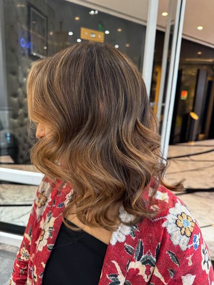 A still shot showcasing a gorgeous caramel blond hair color. This look was created without bleach, resulting in soft, beachy waves with beautiful dimension and shine.