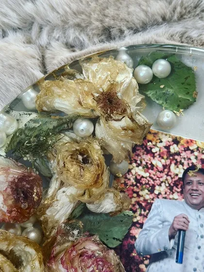A close-up of a circular keepsake celebrating a 25th wedding anniversary, with preserved flowers and pearls surrounding a joyful photo.