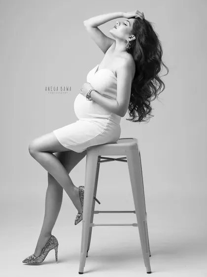 A chic and confident pose on a stool. This black and white image has a high-fashion, editorial feel, perfect for the modern mama.