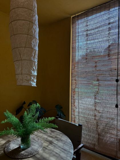 Filtered sunlight through bamboo blinds creates a serene and private atmosphere in this cozy dining nook.