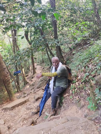 An experienced trekker taking a rest on the steep, forested trail of Kumara Parvatha. It's important to pace yourself on this long hike.