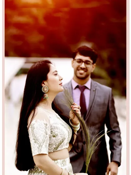 A candid moment during a pre-wedding shoot in a lush green setting. The groom's admiring glance at the bride creates a natural and heartfelt portrait.